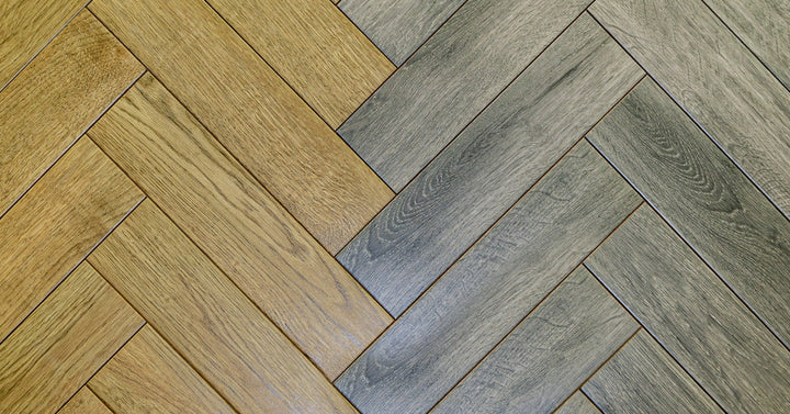 Two laminate floor styles meet in a diagonal pattern, with warm brown on the left and gray wood tone on the right.